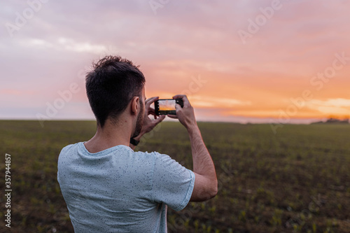 man photographs the sunset on the nature with a smartphone.