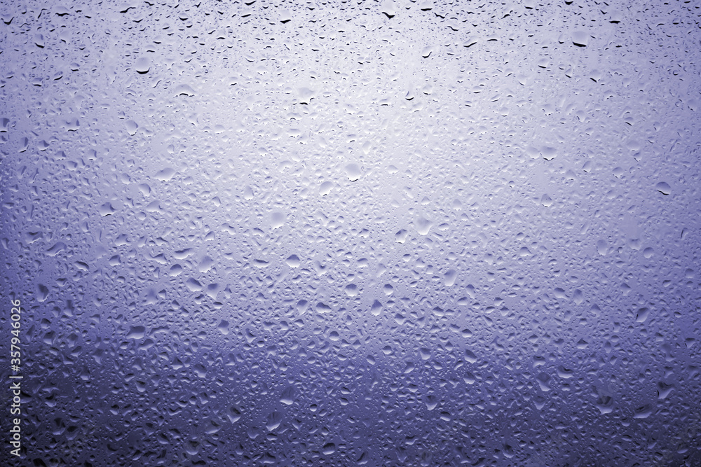 Drops of rain on a window glass with very diffuse landscape navy blue color