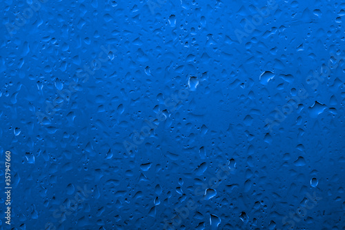 Water drops on glass with vivid medium contrast cobalt blue color