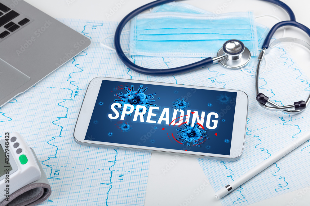 Tablet pc and doctor tools on white surface with SPREADING inscription, pandemic concept Tablet pc and doctor tools on white surface with SPREADING inscription, pandemic concept