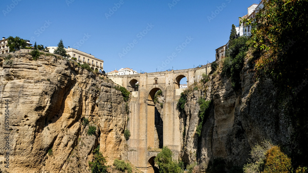 Puente Nuevo famous new bridge in the heart of old village Ronda in Andalusia, Spain. Touristic landmark on a sunny day with buildings in the background. Front view captured from a viewpoint below.