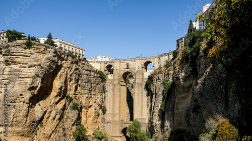 Puente Nuevo famous new bridge in the heart of old village Ronda in Andalusia, Spain. Touristic landmark on a sunny day with buildings in the background. Front view captured from a viewpoint below.