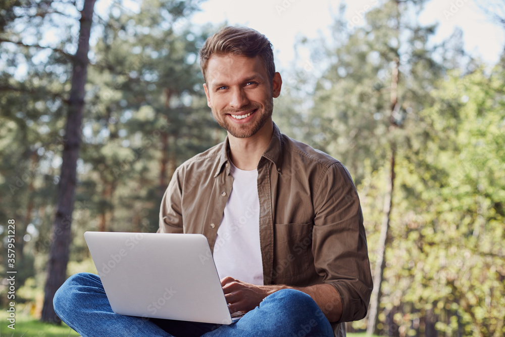 Pleased young male using portable computer outdoors Pleased young male using portable computer outdoors