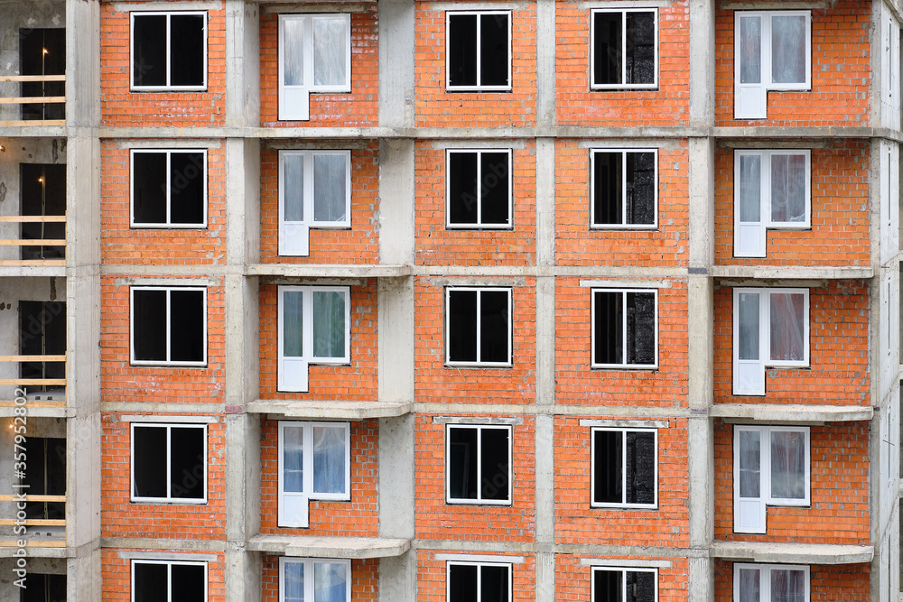 Construction of a new brick residential building with an inset of plastic modern windows.