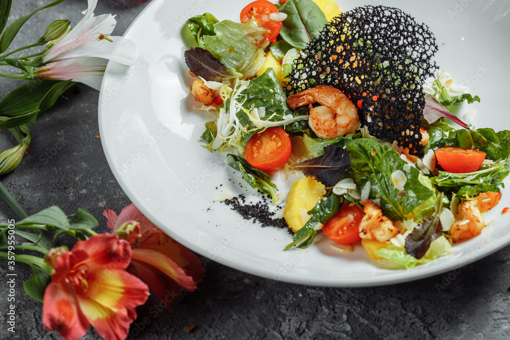 Traditional shrimp and mango salad in a restaurant. Fried shrimp salad with rosemary, mango, cherry tomatoes, salad mix, mango chili sauce. Traditional shrimp and mango salad in a restaurant. Fried shrimp salad with rosemary, mango, cherry tomatoes, salad mix, mango chili sauce.