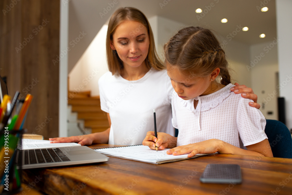 Joyful mother helping cute daughter to study at home Joyful mother helping cute daughter to study at home
