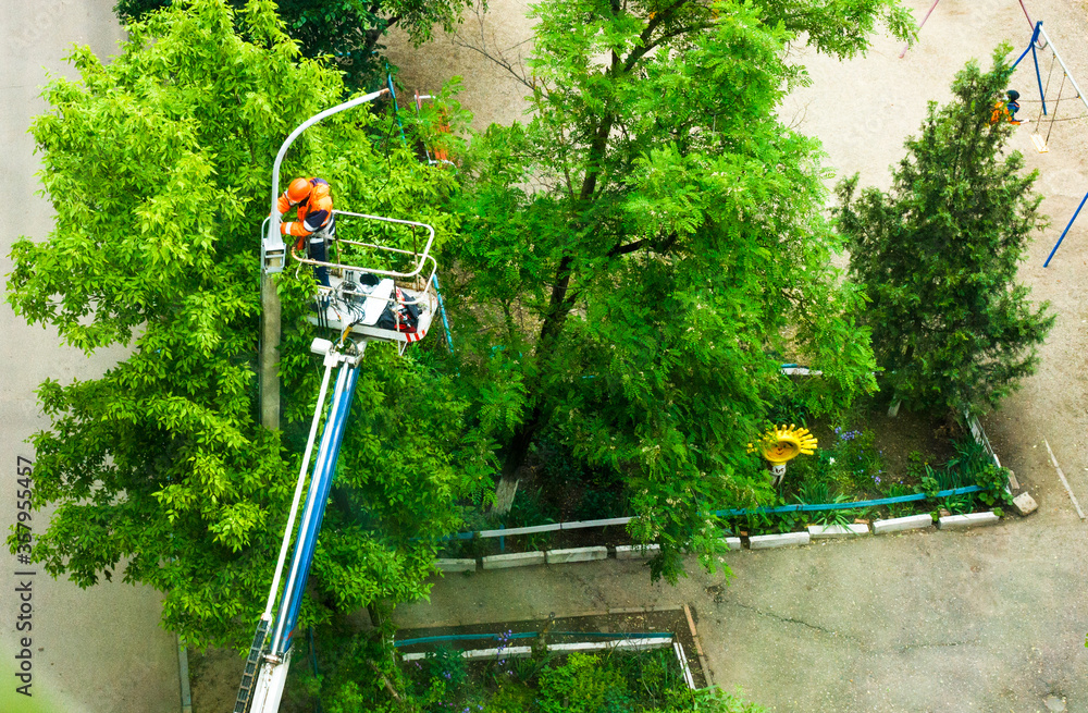 Electrician worker on a long crane arm repair some streetlights. View on top