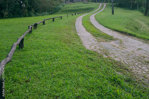 Two long road and wooden fence on green hill