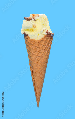 side view fresh pineapple ice cream cone with couple of bites on blue background