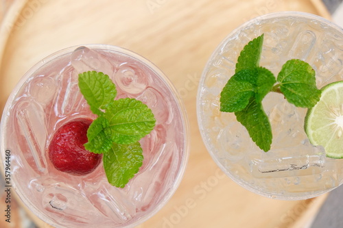 Close-up strawberry with mint on ice drink with blurred background, drink of minerals water with fresh strawberry and mint, ice fresh drink cocktail at traveling trip, beverage of summer concept