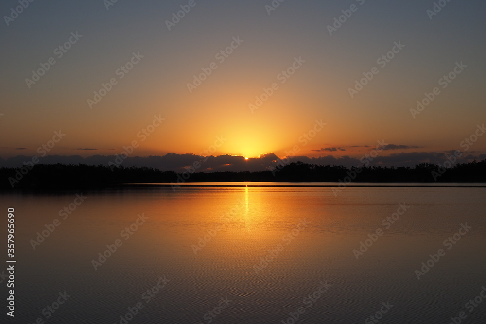 Sunrise over tranquil water of Nine Mile Pond in Everglades National Park, Florida on calm clear morning.