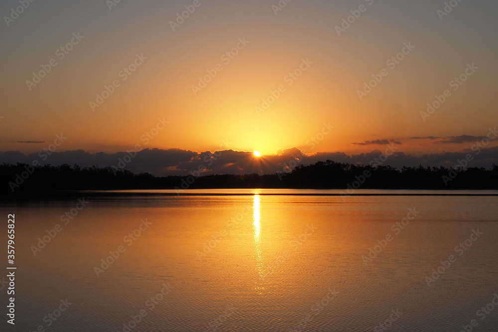 Sunrise over tranquil water of Nine Mile Pond in Everglades National Park, Florida on calm clear morning.