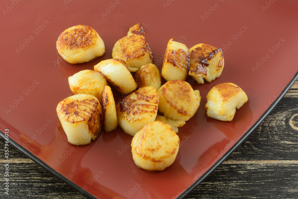 Scallops seafood sauteed with olive oil on red ingredient plate for adding to meal Scallops seafood sauteed with olive oil on red ingredient plate for adding to meal