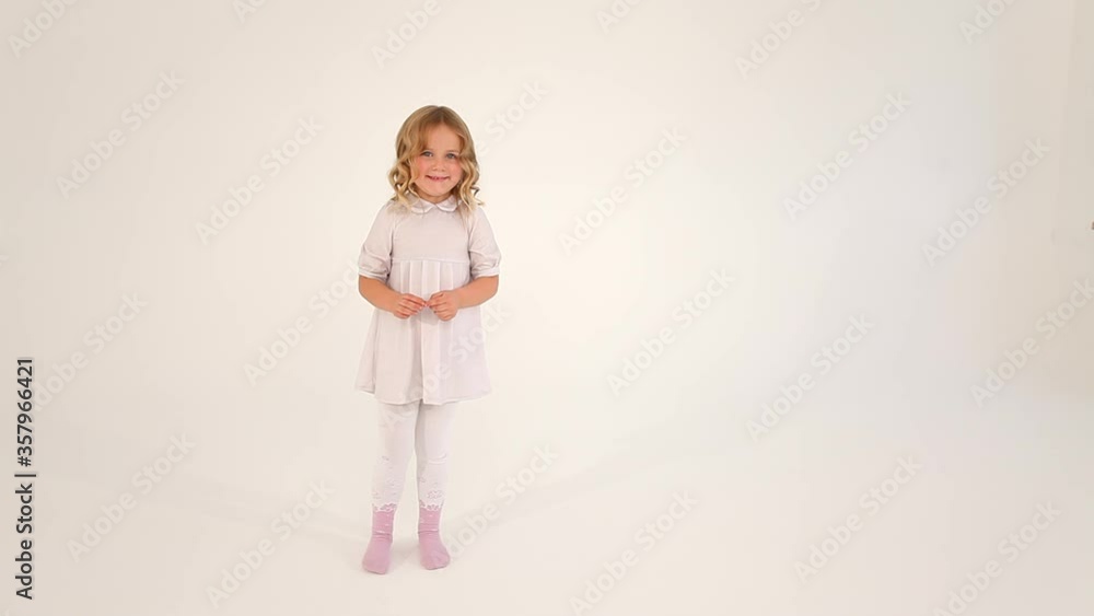 Cute shy little nice small girl child toddler with curly blond hair in white dress drawing big heart in air with fingers Cute shy little nice small girl child toddler with curly blond hair in white dress drawing big heart in air with fingers