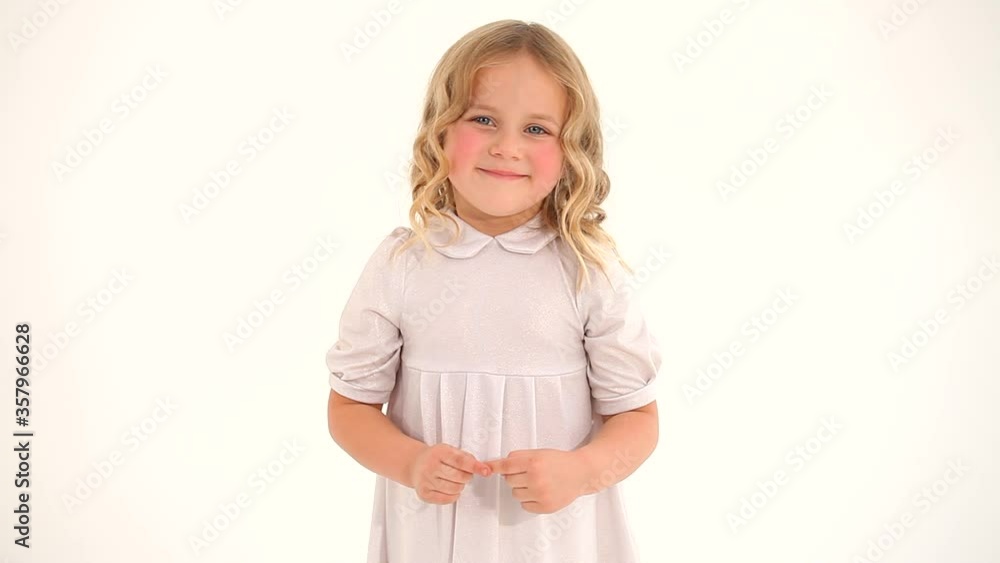Cute little shy small nice girl child toddler with blond curly hair in white dress drawing big heart in air with fingers Cute little shy small nice girl child toddler with blond curly hair in white dress drawing big heart in air with fingers