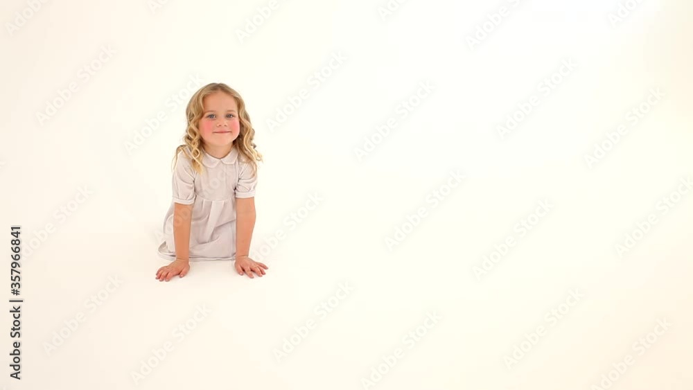 Baby toddler child girl rosy cheeks curly blond hair white dress sitting drawing heart fingers on floor white background Baby toddler child girl rosy cheeks curly blond hair white dress sitting drawing heart fingers on floor white background
