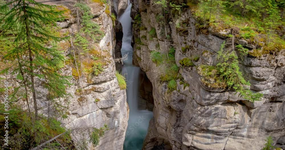 Lockdown shot of waterfall through rocky cliffs at Maligne Canyon in famous national park - Jasper National Park, Canada Lockdown shot of waterfall through rocky cliffs at Maligne Canyon in famous national park - Jasper National Park, Canada