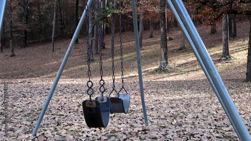 The swings on an empty playground sway in the breeze on an autumn afternoon photo