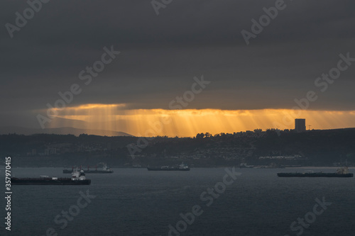 rays of dawn light between the clouds and the sea