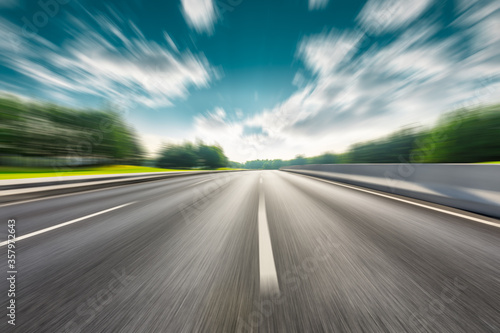 Fast moving asphalt road and green forest landscape. © ABCDstock