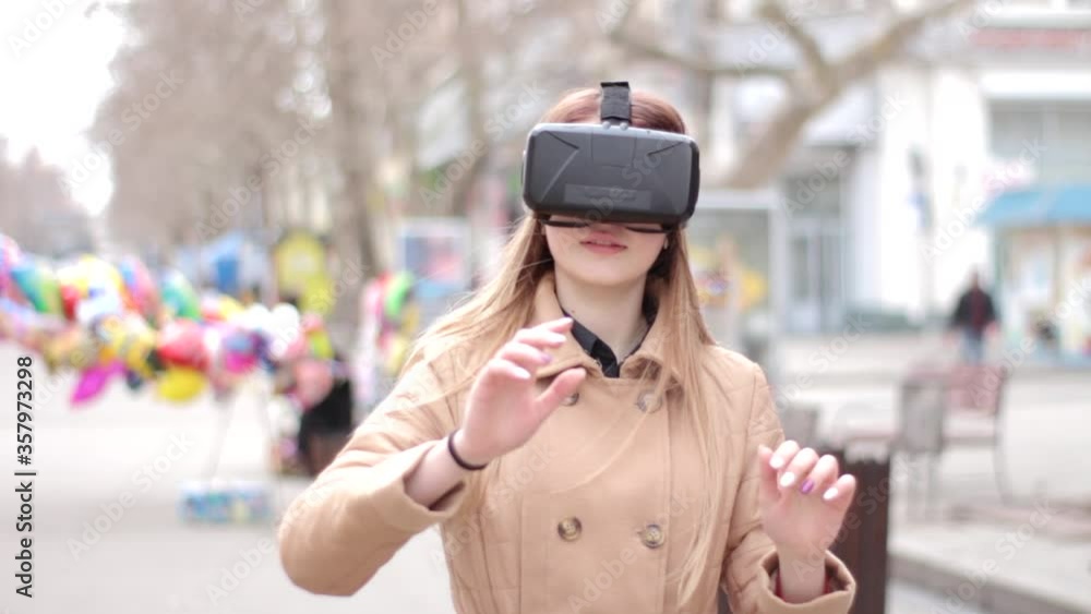 Young happy woman on the street in beige coat playing having fun wearing vr virtual reality headset cyberspace technology glasses Young happy woman on the street in beige coat playing having fun wearing vr virtual reality headset cyberspace technology glasses