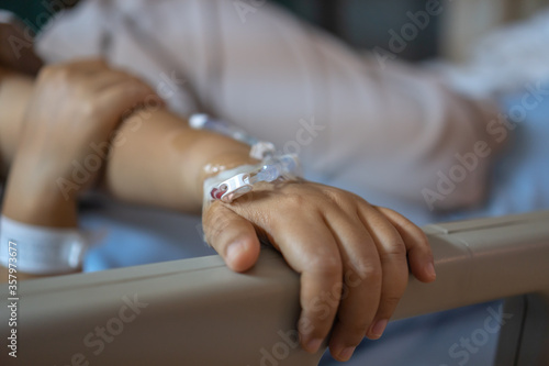 Virus Treatment of Patients saline  Iv drip  young woman hand with medical drip intravenous needle on hospital bed. intravenous therapy  IV  is a therapy that delivers fluids directly into vein