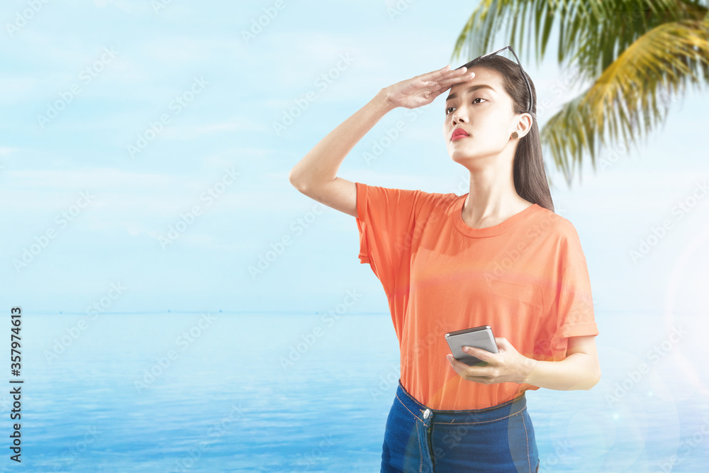 Asian woman holding mobile phone looking at scenery view on the beach Asian woman holding mobile phone looking at scenery view on the beach