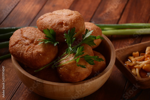 Stuffed Buns (Pirozhki) in wooden bowl on the wooden background. With green onions ,and herbs. Homemade pasty, Russian stuffed pastry. photo