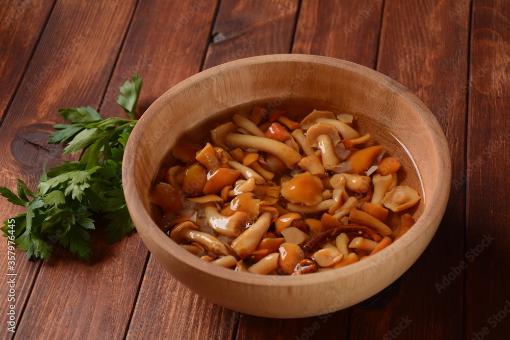 Homemade pickled honey agarics mushrooms with onion slices in wooden bowl. Marinated mushrooms in a bowl on wooden background.Fermented healthy food. Homemade pickled honey agarics mushrooms with onion slices in wooden bowl. Marinated mushrooms in a bowl on wooden background.Fermented healthy food.