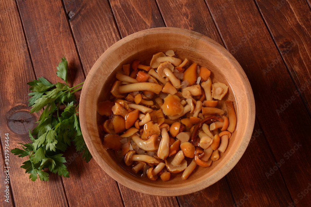 Homemade pickled honey agarics mushrooms with onion slices  in wooden bowl. Marinated mushrooms in a bowl on  wooden background.Fermented healthy food.