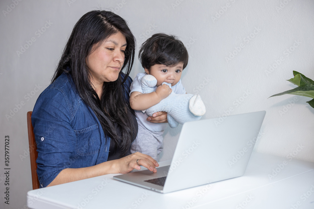 Mexican Mother working from home while her son distracts her and drawing attention Mexican Mother working from home while her son distracts her and drawing attention