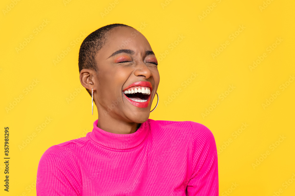 Happy optimistic African American woman in colorful pink clothes laughing isolated on yellow background - obrazy, fototapety, plakaty 
