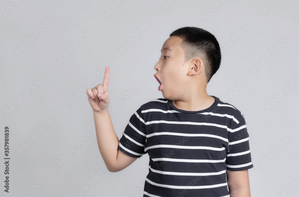 Asian boys studio portrait on gray background with amazed and surprised looking and pointing with fingers and raised arms. Asian boys studio portrait on gray background with amazed and surprised looking and pointing with fingers and raised arms.