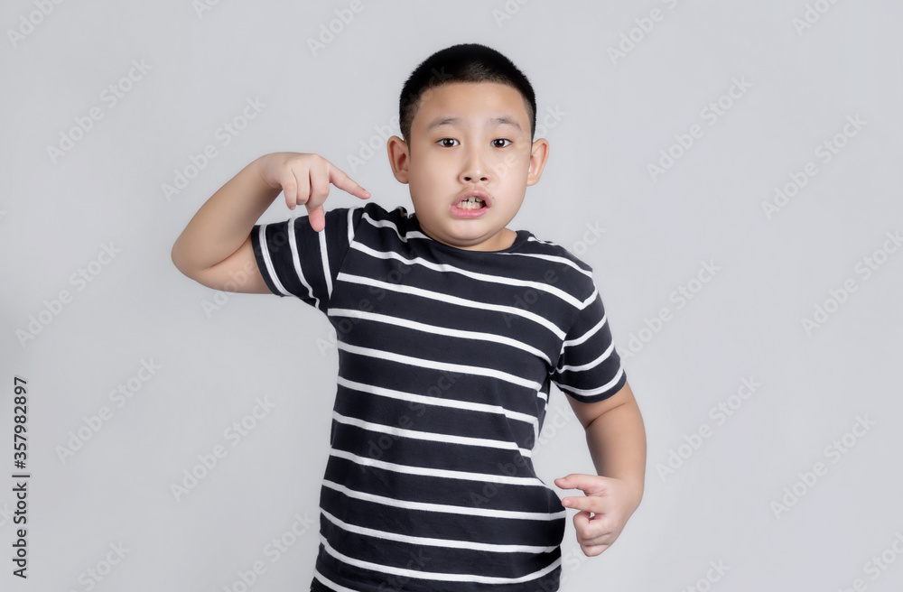 Asian boys studio portrait on gray background with finger surprised ahead, open mouth amazed expression, something in front Asian boys studio portrait on gray background with finger surprised ahead, open mouth amazed expression, something in front