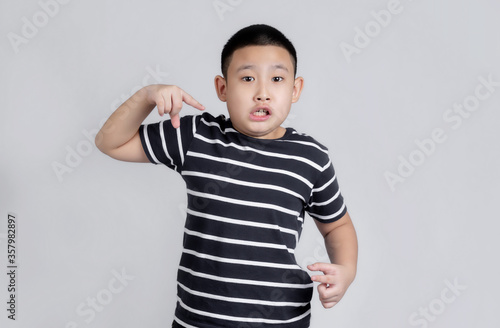 Asian boys studio portrait on gray background with finger surprised ahead, open mouth amazed expression, something in front
