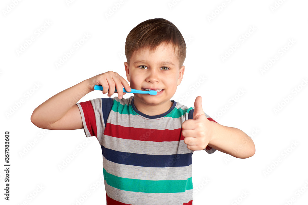 Smiling boy brushes his teeth and shows a thumbs up, isolated on a white background