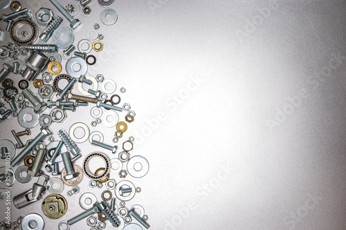 various screws, bolts and nuts on metallic grey background. home repair work concept