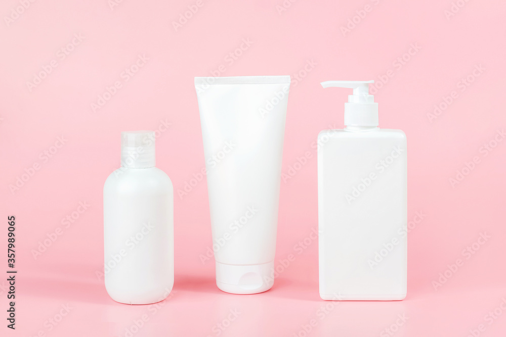 Set of care cosmetic for skin, body or hair. Three white blank cosmetics bottles, tube on pink background. Spa Cosmetic Beauty Concept. Front view Mockup Set of care cosmetic for skin, body or hair. Three white blank cosmetics bottles, tube on pink background. Spa Cosmetic Beauty Concept. Front view Mockup