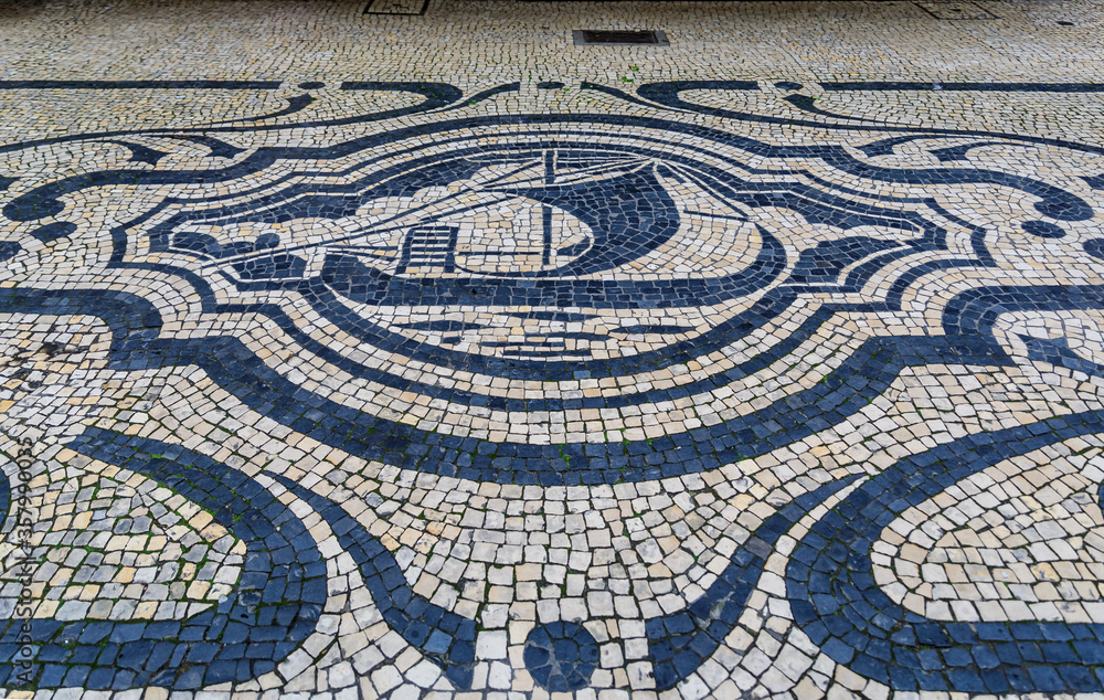 Antique cobblestone mosaic with a ship on a shopping street Rua de Sampaio Bruno sidewalk in old town of Porto, Portugal