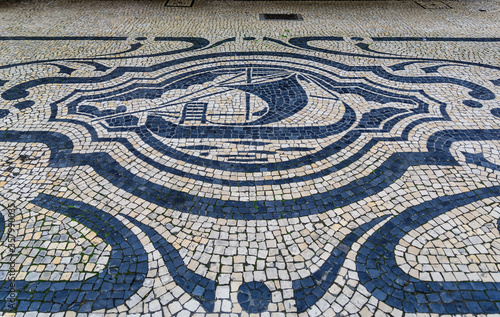 Antique cobblestone mosaic with a ship on a shopping street Rua de Sampaio Bruno sidewalk in old town of Porto, Portugal
