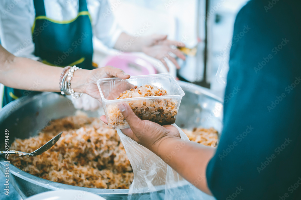 The hands of the poor receive food that volunteers share to alleviate hunger: the concept of donating food to the poor