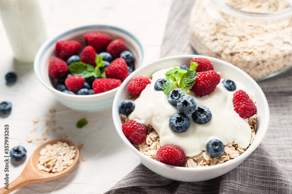 Breakfast, oatmeal with blueberry and raspberry on white bowl in the morning. Breakfast, oatmeal with blueberry and raspberry on white bowl in the morning.