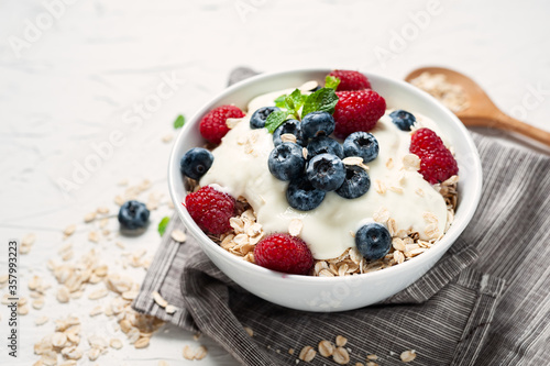 Breakfast, oatmeal with blueberry and raspberry on white bowl in the morning.