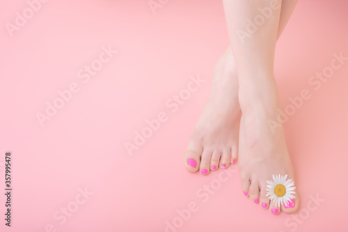 women s feet with pedicure on nails and chamomile flower decoration. Skincare concept