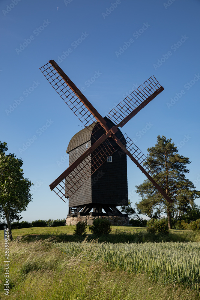 Old black mill with fields around it