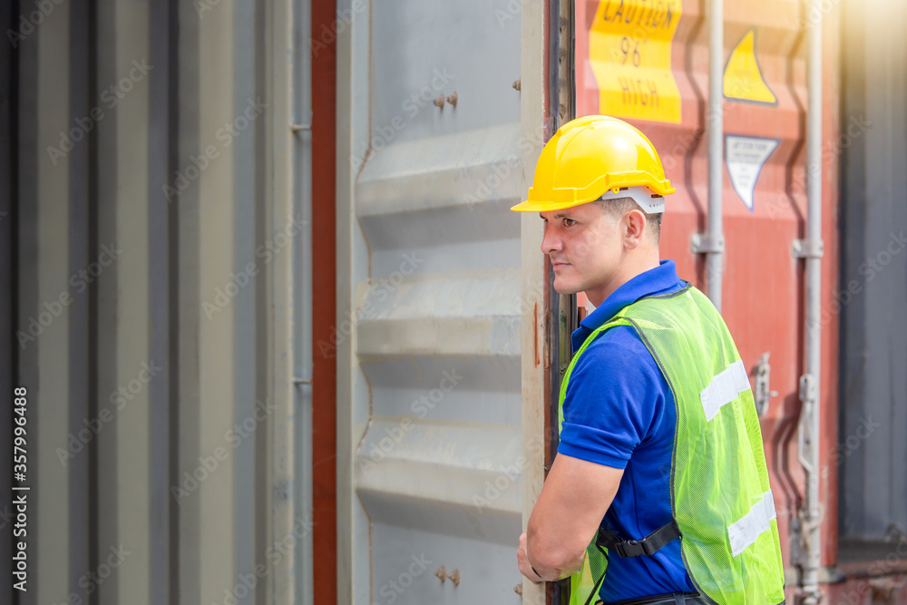 Foreman worker in hard hat and safety vest checking containers box from cargo Foreman worker in hard hat and safety vest checking containers box from cargo