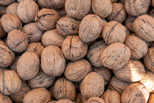 Background of the dried walnuts. Walnut meats are available in two forms; in their shells or shelled. The meats may be whole, halved, or in smaller portions due to processing.