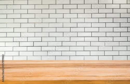 Wood table in front of white brick wall background. Brown wooden desk empty counter in front of the room. Copy space for text and ideal for product placement.