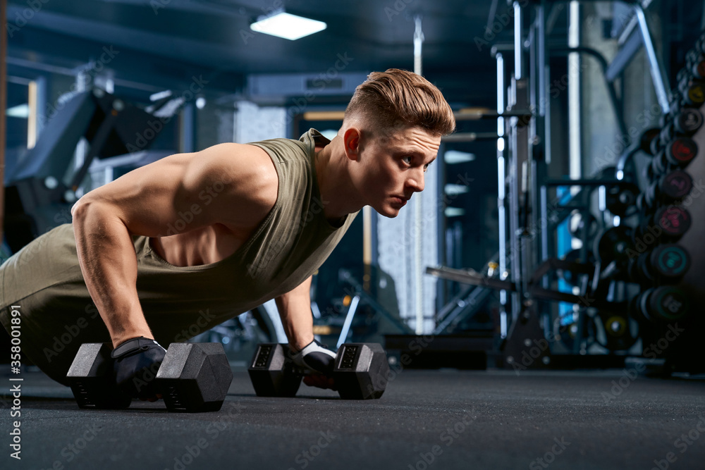 Muscular man doing push ups using dumbbells. Muscular man doing push ups using dumbbells.