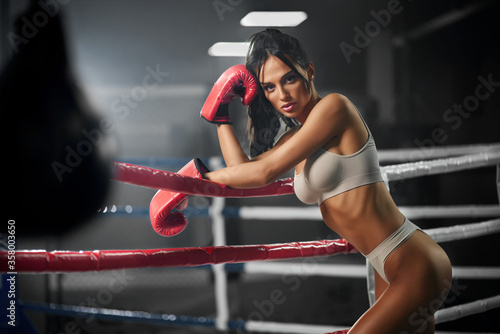 Female fighter posing in gloves near ring.